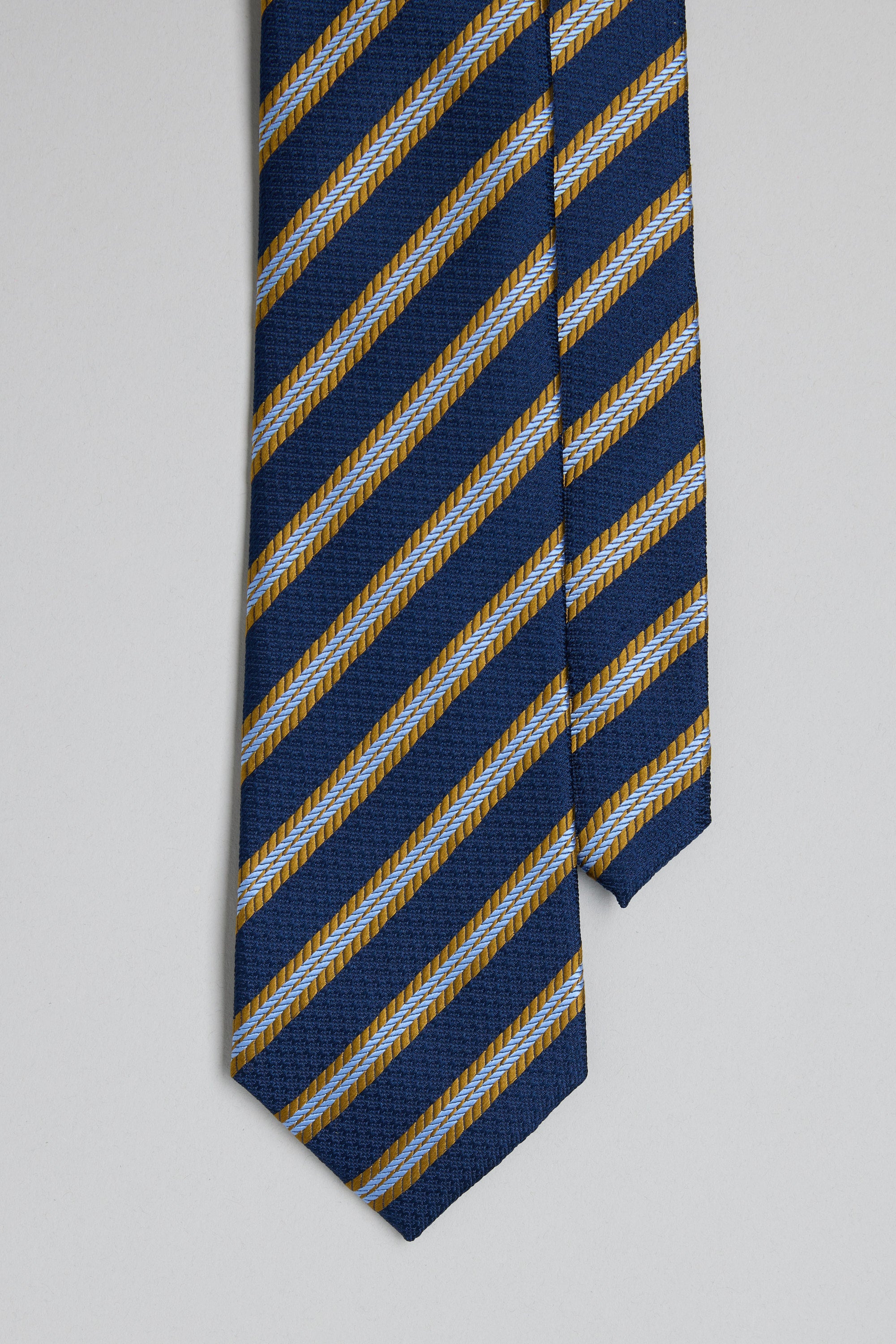 The Barkers Milton Stripe Tie is a blue silk tie with diagonal gold and light blue stripes and classic jacquard prints, shown on a plain light gray background.