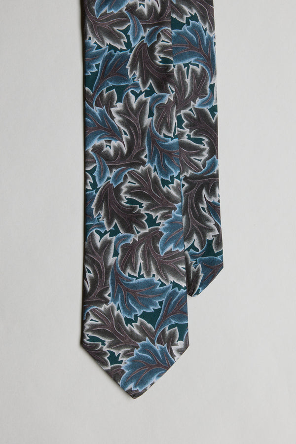The Liberty Midnight Canopy Tie by Liberty is a men's formal accessory, featuring bold blue, teal, and gray leaf patterns on black Tana Lawn cotton, presented on a light gray background.