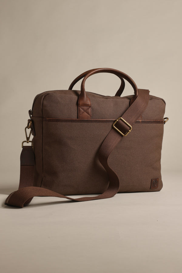 The Barkers Redford Canvas Laptop Bag, made from premium leather and organic cotton with gold-tone hardware, a top handle, and adjustable shoulder strap, is shown on a neutral background.
