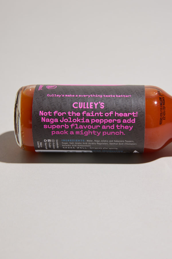 A bottle of Culley’s Malevolent Ghost Hot Sauce lies on its side. The label reads, “Not for the faint of heart! Naga Jolokia peppers add superb flavour and they pack a mighty punch,” with ingredient details below.