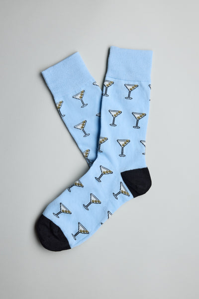 The Barkers Bond Martini Sock is a light blue cotton blend pair with black heels and toes, featuring martini glasses with green olives—stylish dress socks for any occasion.