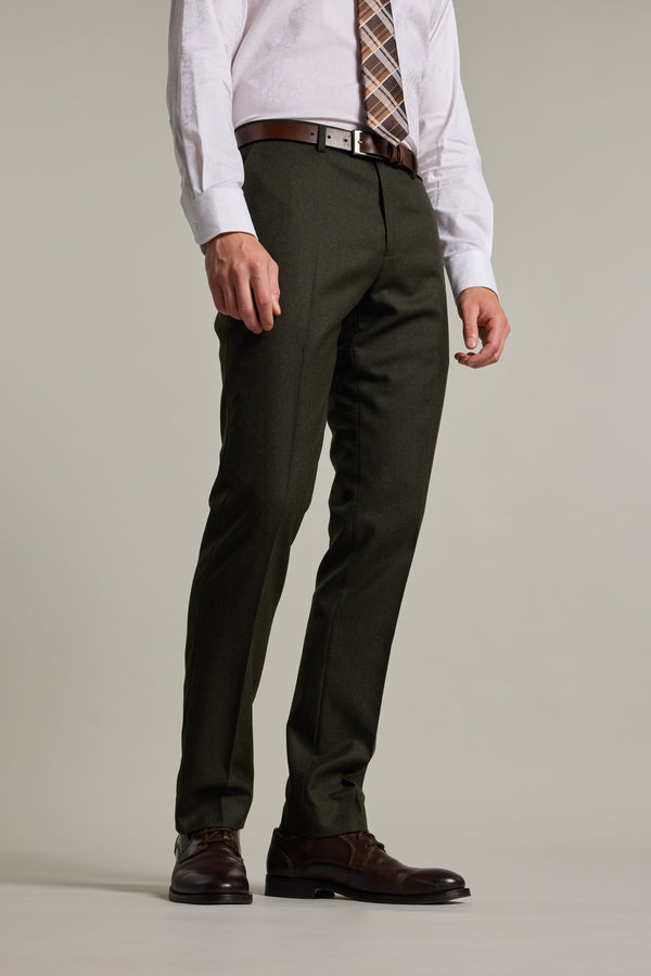 A man wearing Barkers Howard Suit Trouser in forest green, paired with a white shirt, brown belt, plaid tie, and brown dress shoes stands against a plain light background. His face is not visible.