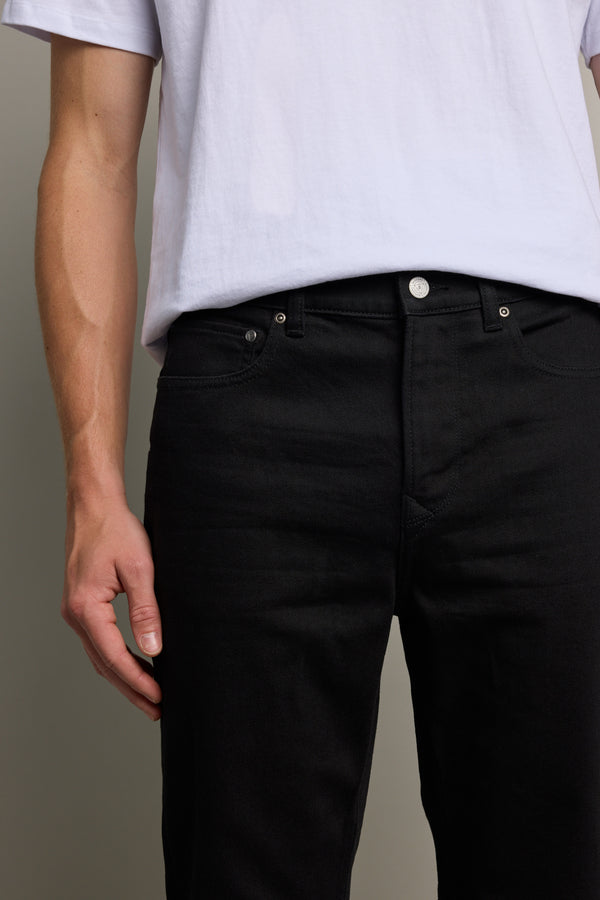 Person wearing a white t-shirt and Barkers Nomad Denim Taper Jean, visible shoulders to thighs.
