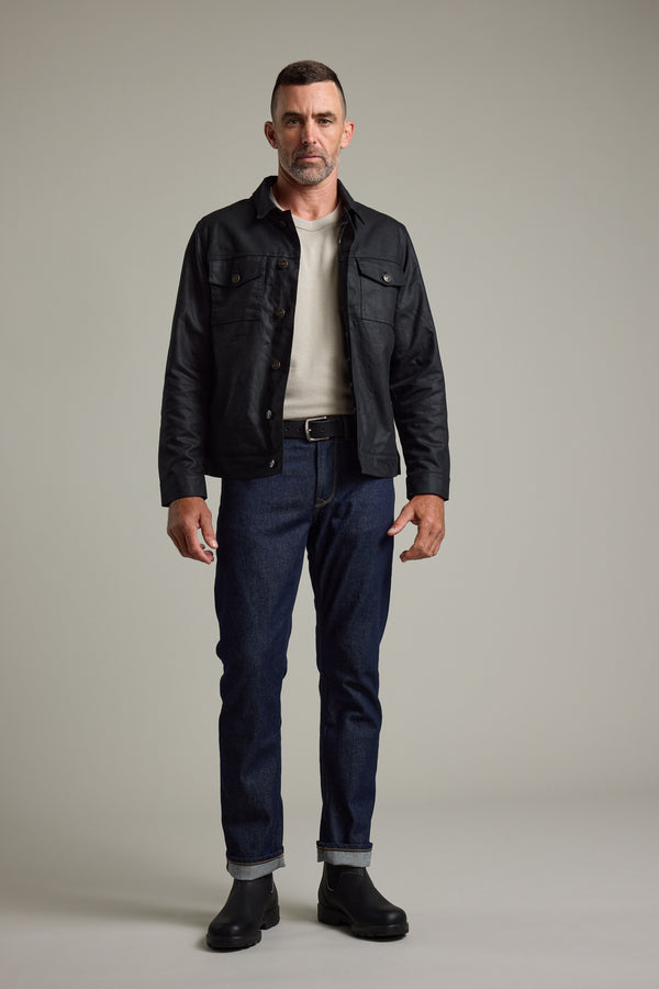 Man in Barkers Benson Waxed Cotton Jacket, white shirt, dark jeans, and black boots.