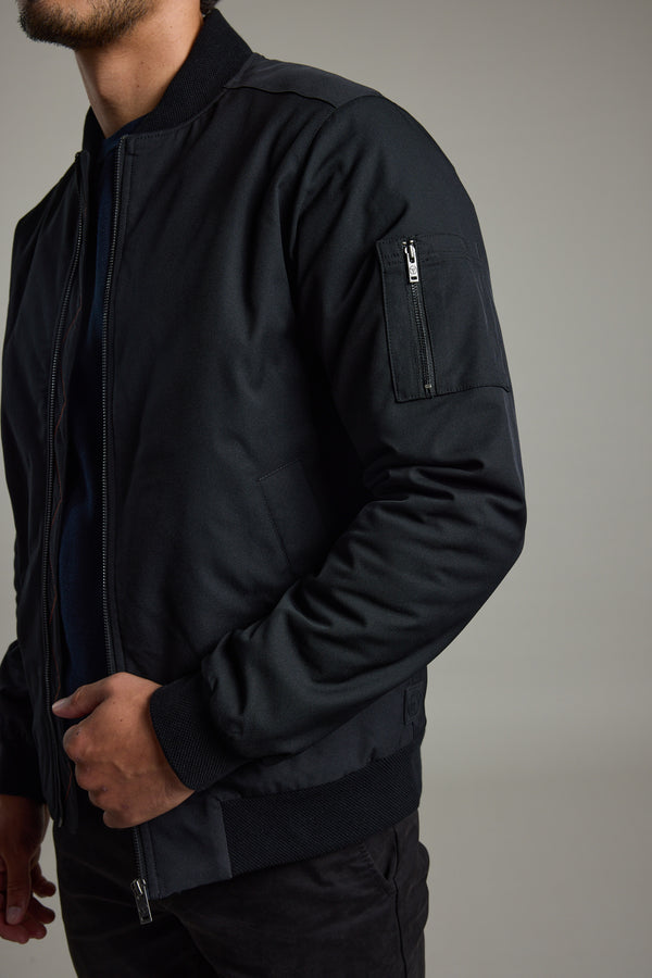 Man in Barkers Dunhill Bomber Jacket, hand in pocket, against a plain background.