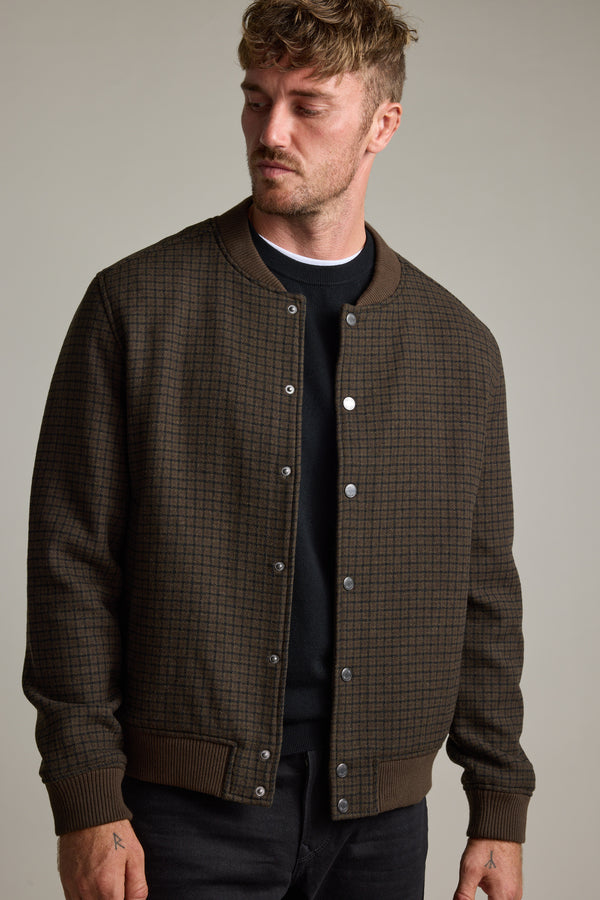 Man in Barkers Leland Wool Bomber Jacket over a black shirt, looking down to the side.