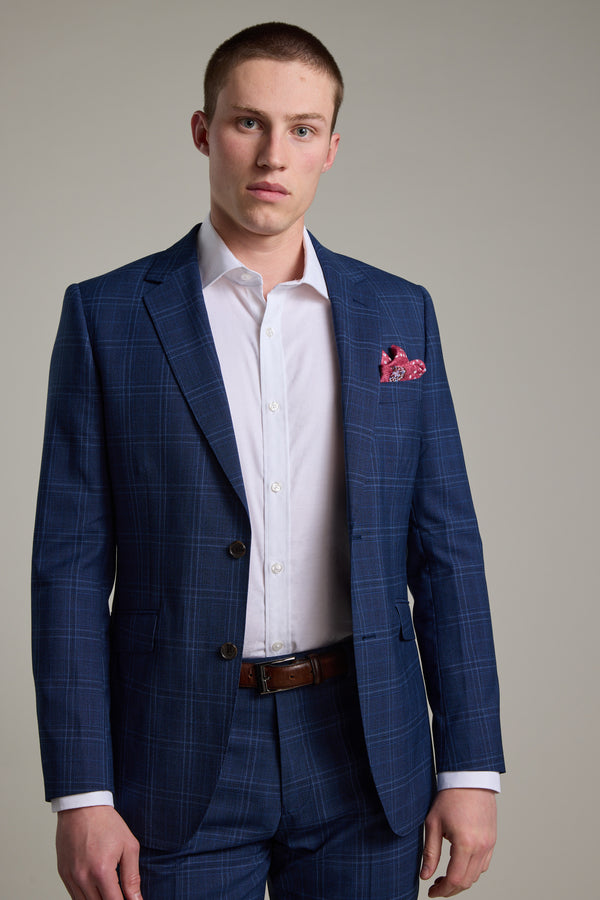 A young man with short hair models the Barkers Leonard Check Suit Jacket, paired with a white dress shirt and red pocket square. He stands against a plain, light background, looking directly at the camera with a neutral expression.