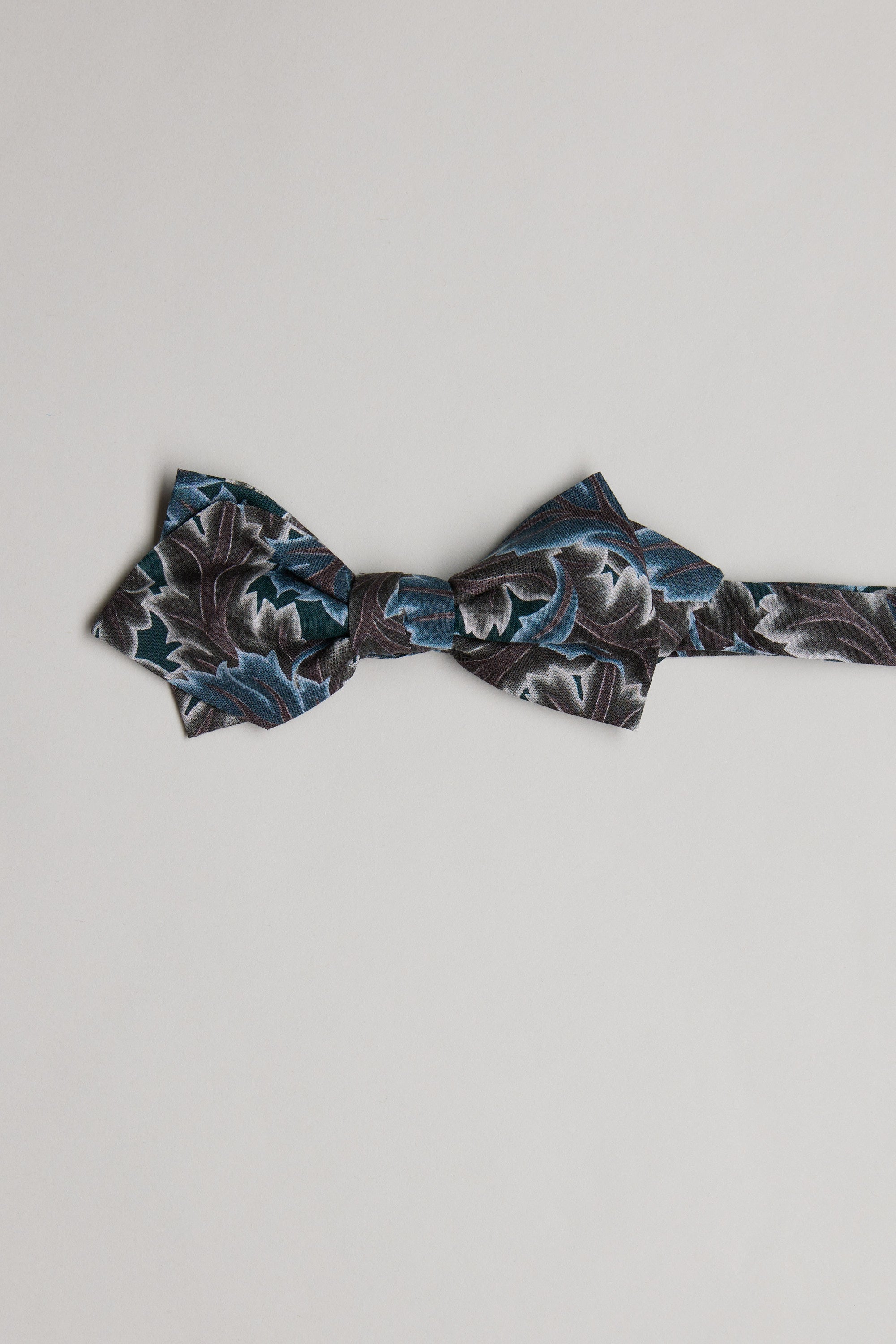 The Liberty Midnight Canopy Bow Tie by Liberty is handmade in New Zealand from premium Tana Lawn cotton and showcases dark blue, black, and gray patterns on a light background.