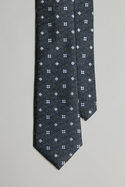 The Barkers Enright Flower Tie features a dark base with a small white and blue geometric floral pattern, shown against a plain light background.