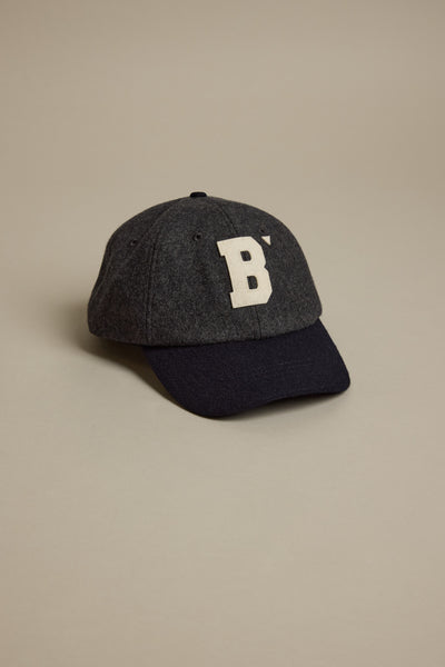 The Darcy Woollen Cap by Barkers, in dark gray wool with a black bill and a bold white 'B' patch logo on the front, is shown against a plain light beige background.