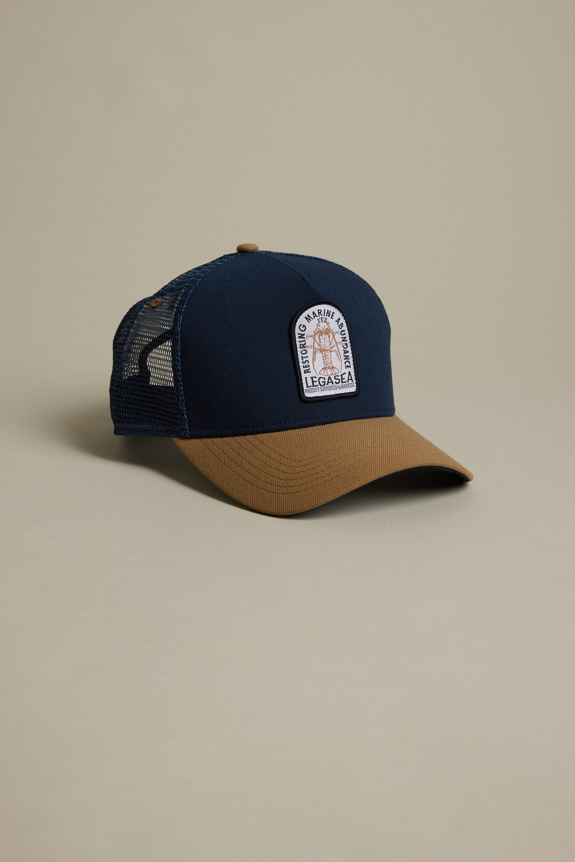 The Legasea Crayfish Trucker Snapback Cap features a navy front and bill, brown brim, black mesh back, and a rectangular crayfish patch logo. Classic trucker snapback style from Legasea with a standout two-tone design.