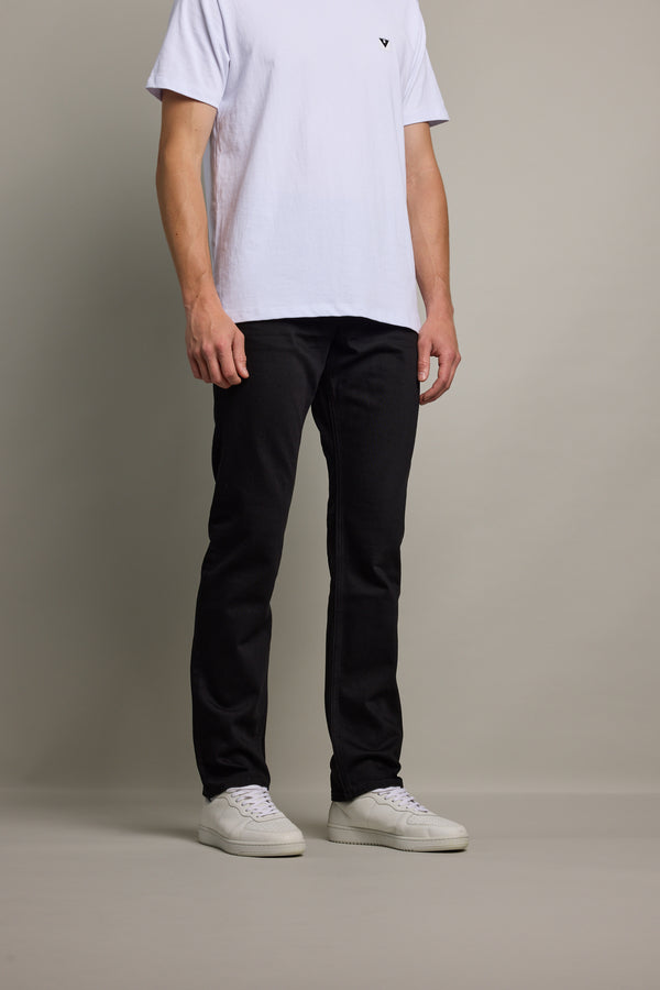 A man in a white tee and Barkers Nomad Denim Taper Jean stands against a plain background.