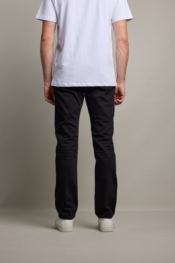 Person facing away in Barkers Nomad Denim Taper Jean, white tee, and white shoes.