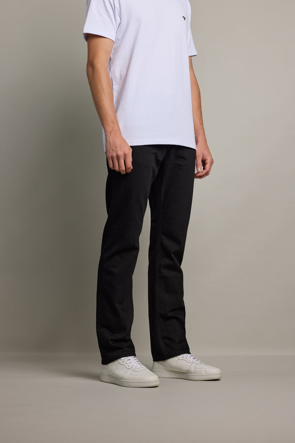 A man in a white t-shirt and Barkers Wanderer Denim Straight Jean stands against a plain background.