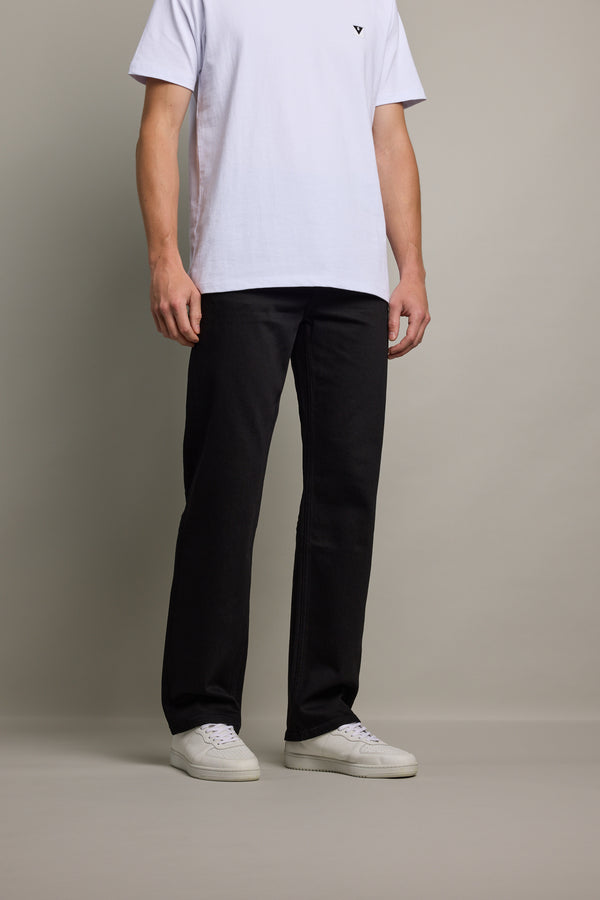 Person wearing Barkers Drifter Denim Relax Jean with a white tee and sneakers against a plain backdrop.