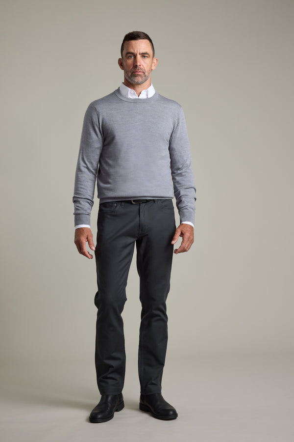 Man in a gray Barkers Skyland ZQrx Merino Crew, dark pants, and black shoes on plain background.