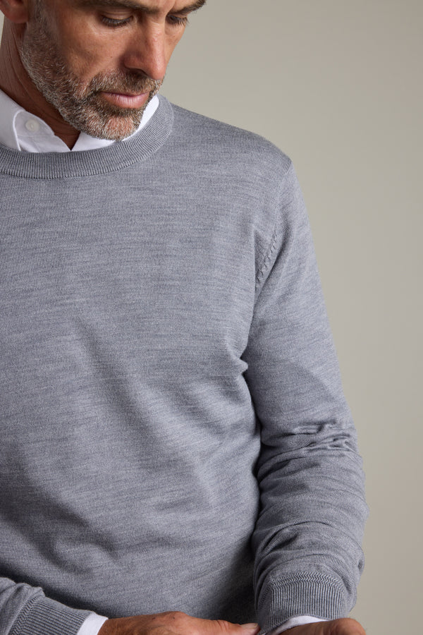 Man wears Barkers Skyland ZQrx Merino Crew, white shirt, looking down, chest up.
