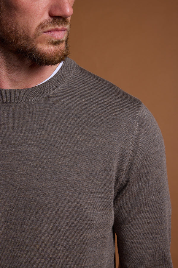 A man with a short beard and mustache wears the Barkers Skyland ZQrx Merino Crew, a brown merino wool sweater, over a white shirt. Shown from the shoulders up against a plain brown background, his face is partially visible, looking left.