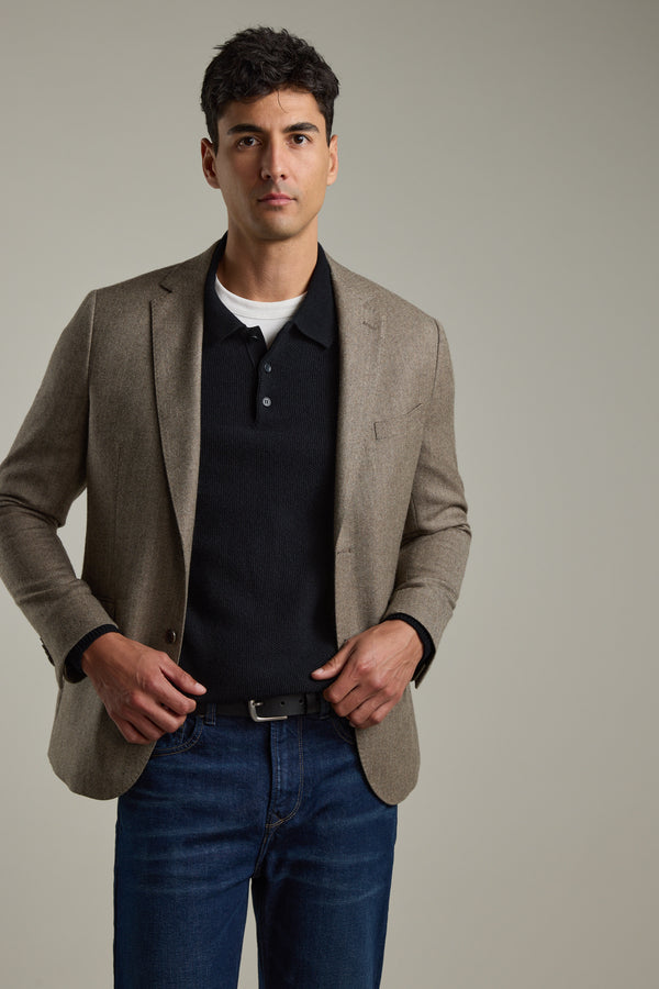 Man in a brown blazer, Barkers Ainsley Woollen Long Sleeve Polo, and jeans on a plain background.