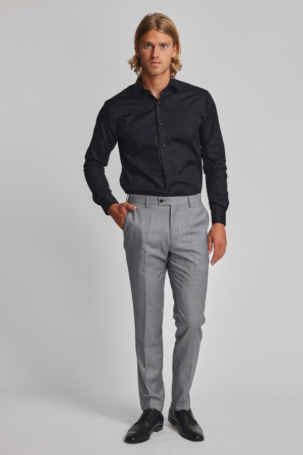 A man faces forward wearing the Barkers Tribeca Reg Cuff Shirt in black, paired with light gray dress pants and black dress shoes, set against a plain light background.