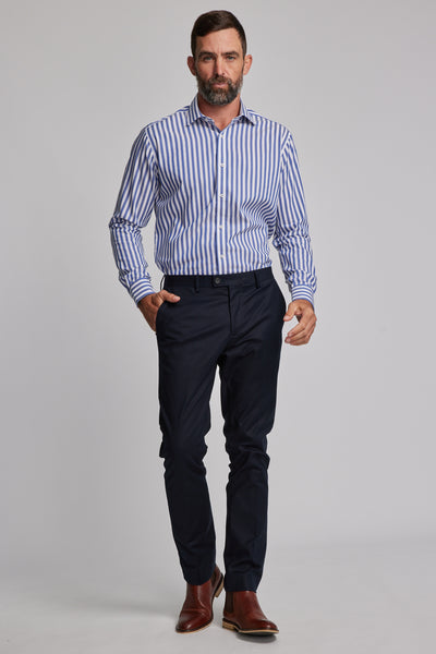 A man with short brown hair and a beard wears the Barkers Midway Shirt in a tailored fit, paired with dark navy dress pants and brown dress shoes, walking confidently against a plain light gray background.