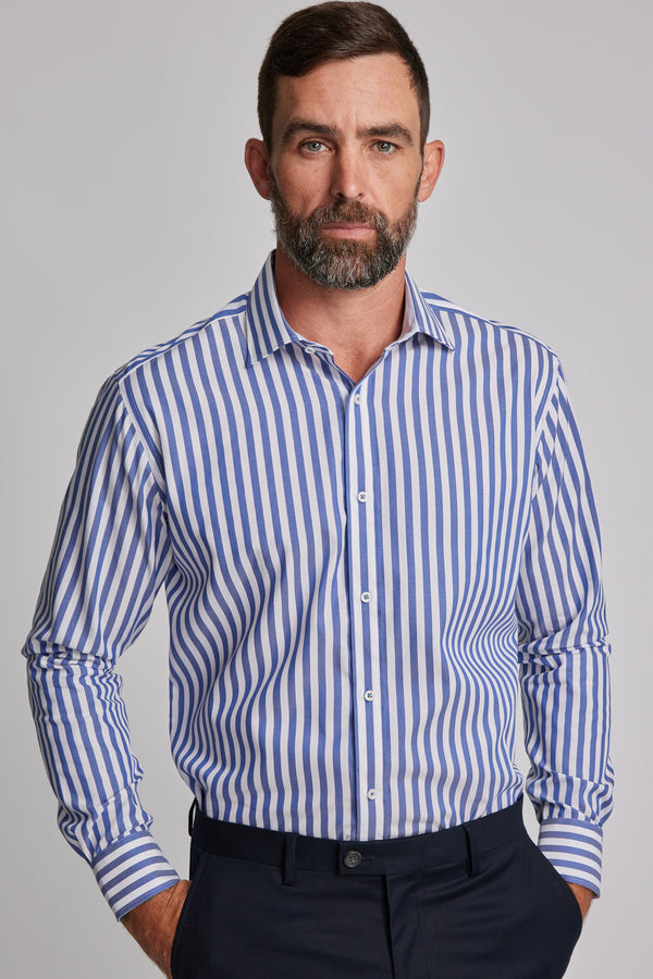 A man with short dark hair and a beard models the Barkers Midway Shirt, a tailored fit blue striped business shirt, paired with dark trousers against a plain light gray background.