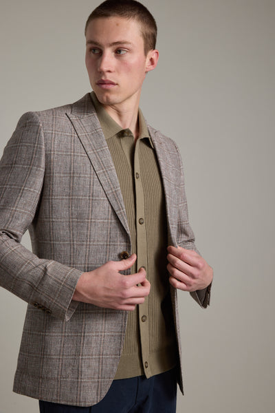A young man with short hair models the Barkers Madison Check Blazer over an olive green shirt, looking left against a plain background—a stylish choice for modern summer workwear.