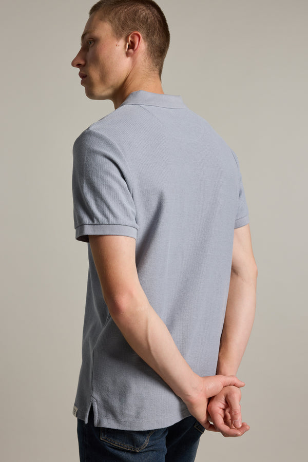 Man in Barkers Winfield Textured Polo, open collar, hands clasped behind back, facing left.