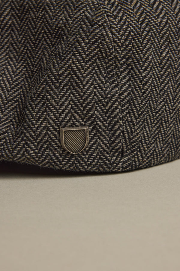 A close-up of the Brixton Brood Snap Cap in herringbone wool with a small metallic emblem.
