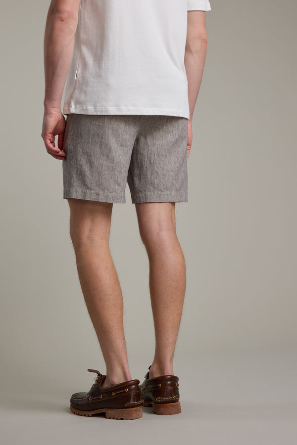 A person faces away from the camera in a white short-sleeve shirt and Barkers' Woodley Weekend Short in light gray with an elastic waistband, paired with brown boat shoes. The backdrop is plain and neutral.