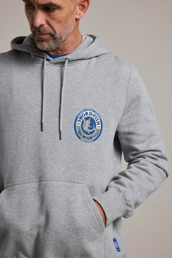 A man wears the Swordfish Mojo Logo Hoody in light gray, featuring the brand’s logo on the chest, with one hand in its front pocket. Ideal for fans of Swordfish Mojo.