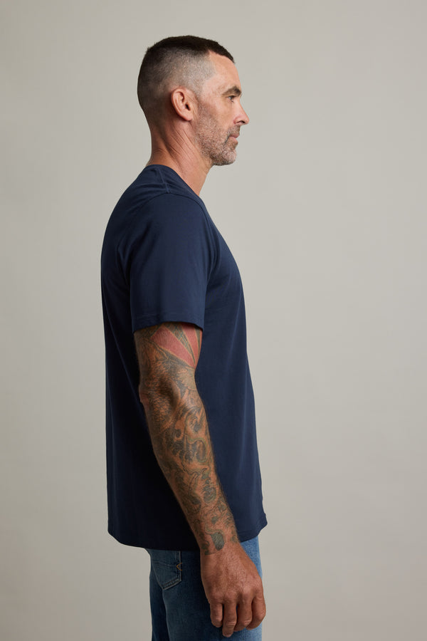 Tattooed man in Barkers Good Earth Cotton Essential Tee, standing in profile against plain background.