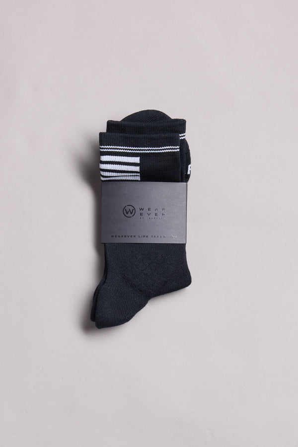 A pair of WearEver Active Socks in black with white top stripes, neatly folded and wrapped in a gray WearEver band. Made in New Zealand, these socks are set against a plain light gray background.