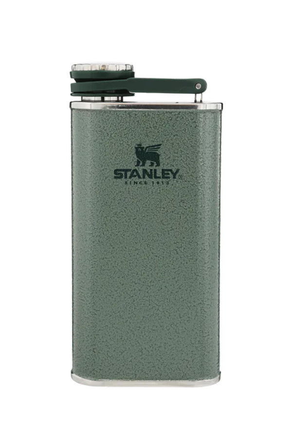 The Stanley Classic Easy Fill Wide Mouth Flask (235ml) features a green stainless steel body with textured surface, silver edges, and a hinged cap. The Stanley logo and “Since 1913” appear on the front. The flask stands upright on a white background.