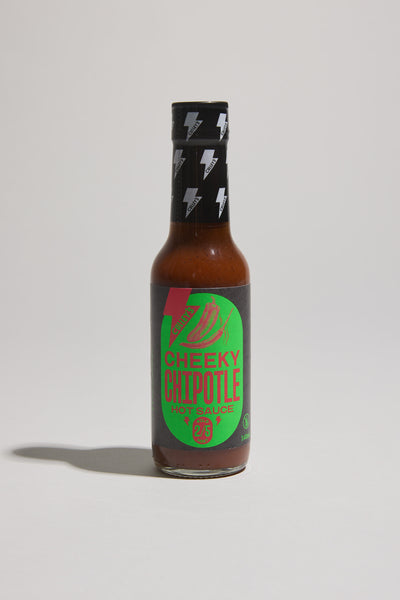 A bottle of Culley’s Cheeky Chipotle Hot Sauce stands upright on a light surface, its green and black label with chili graphic promising smoky chipotle and roasted red bell pepper flavor—perfect for spicing up any Mexican sauce.