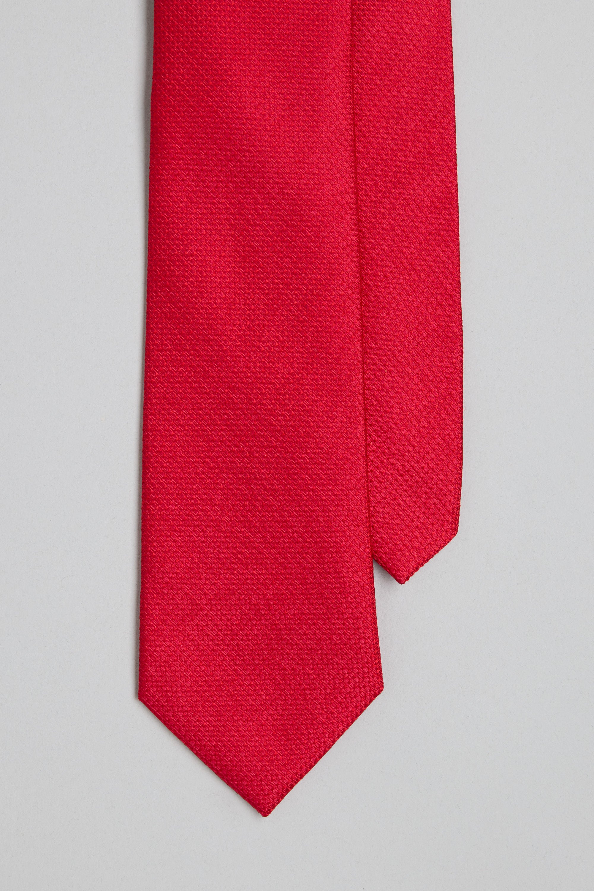 A close-up of the Barkers Castle Texture Tie, a vivid red silk tie featuring a jacquard print, displayed flat on a light grey background.