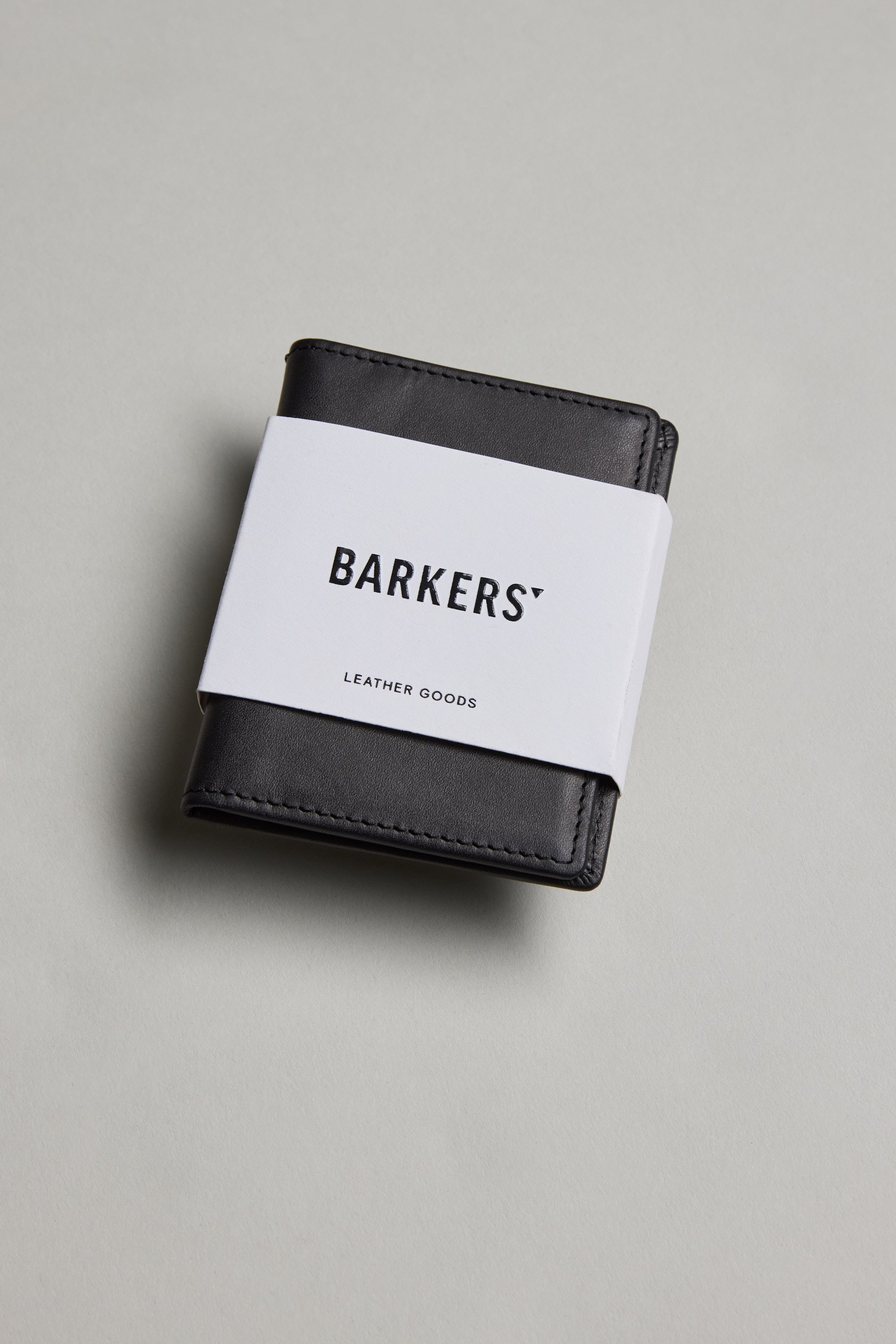 The Marlin Leather Slim Wallet by Barkers, a sustainable wallet wrapped with a white paper band labeled Barkers, is displayed on a light gray surface.