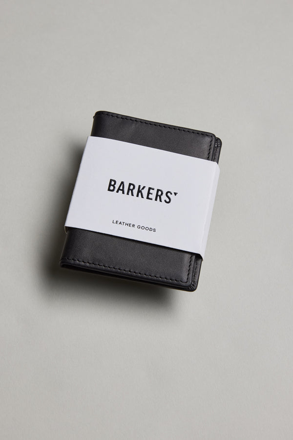 The Marlin Leather Slim Wallet by Barkers, a sustainable wallet wrapped with a white paper band labeled Barkers, is displayed on a light gray surface.