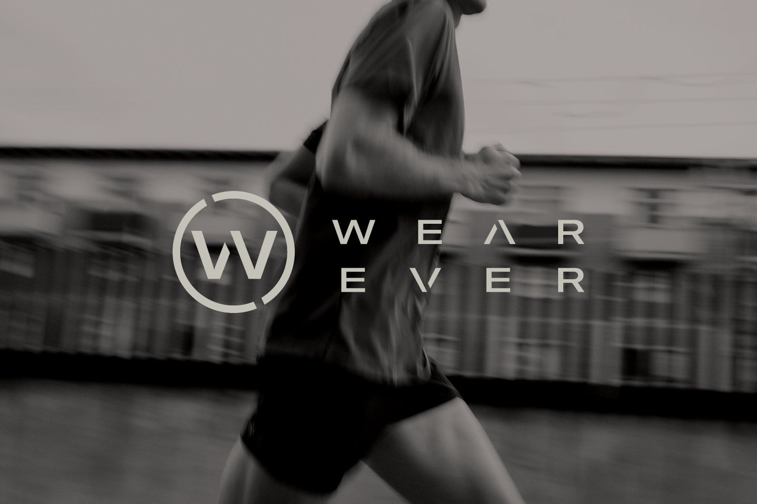A blurred black-and-white photo of a person running, with the Wear Ever logo and text overlayed in the center of the image.