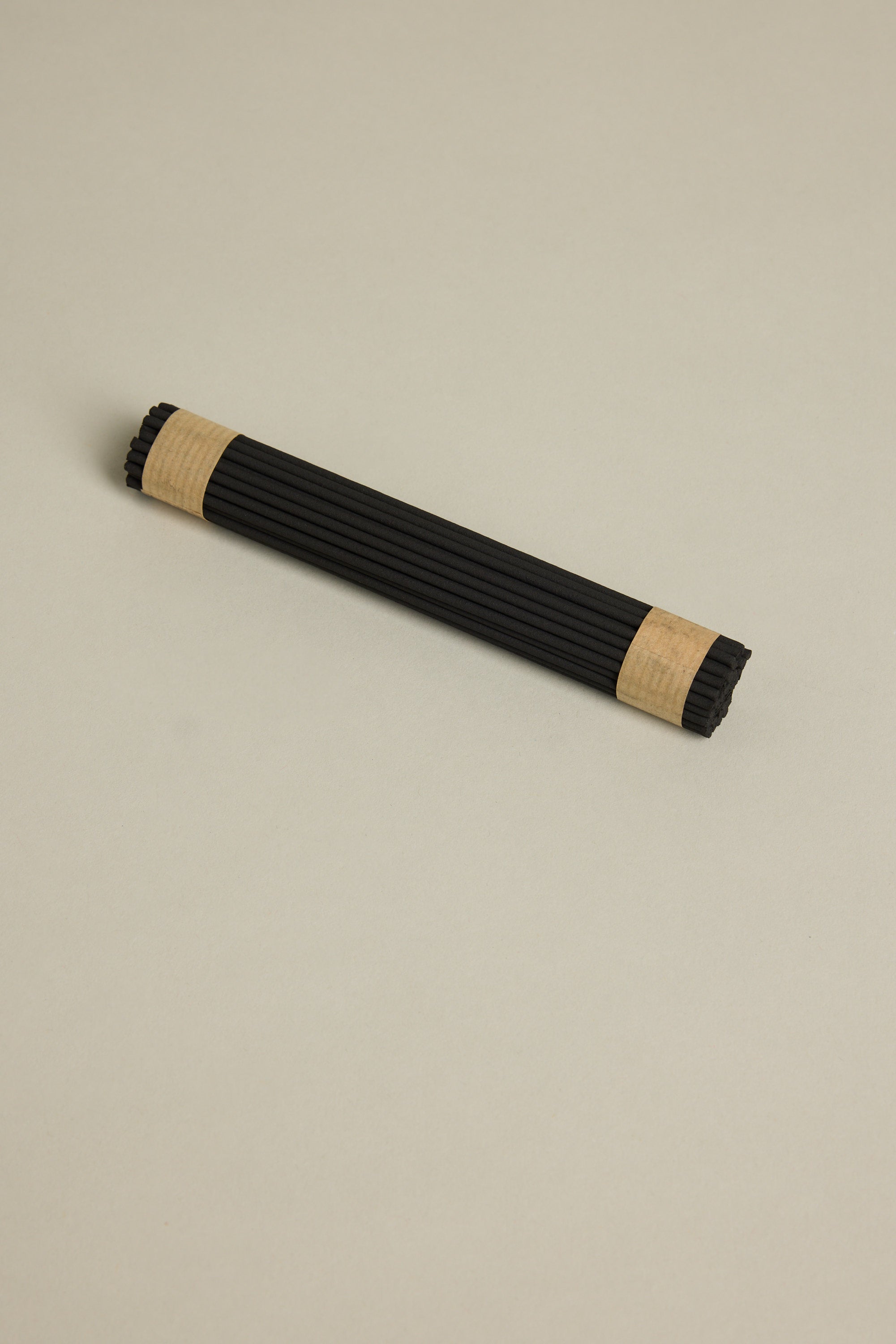 A bundle of Earl of East EoE Onsen Japanese Incense Sticks, featuring a refreshing peppermint scent, is secured with kraft paper bands at both ends and displayed on a plain light beige surface.