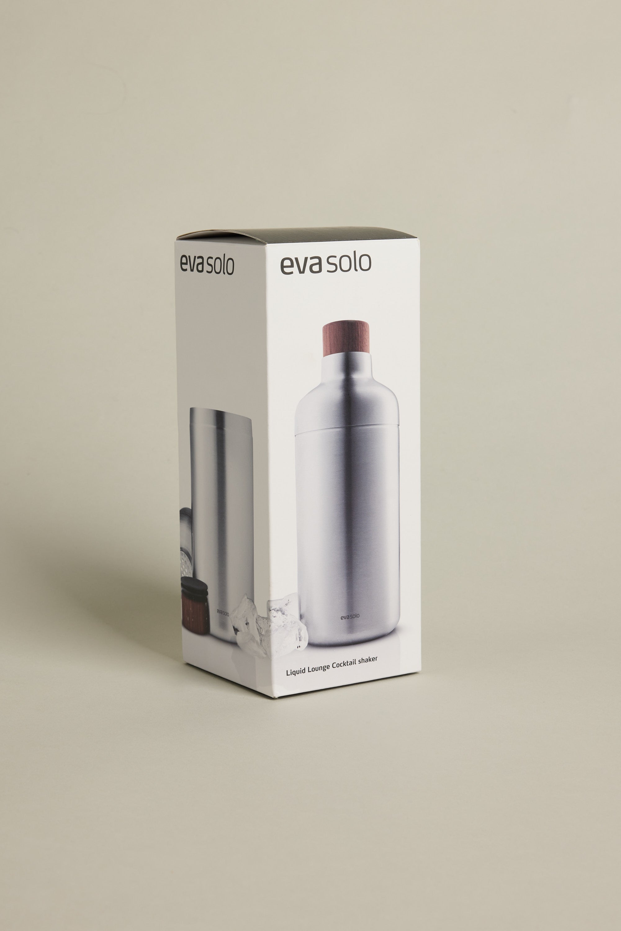 A box of Other Liquid Lounge Cocktail Shaker, a home bar essential featuring the stainless steel shaker with a wooden cap shown on the packaging front and side, set against a neutral background.