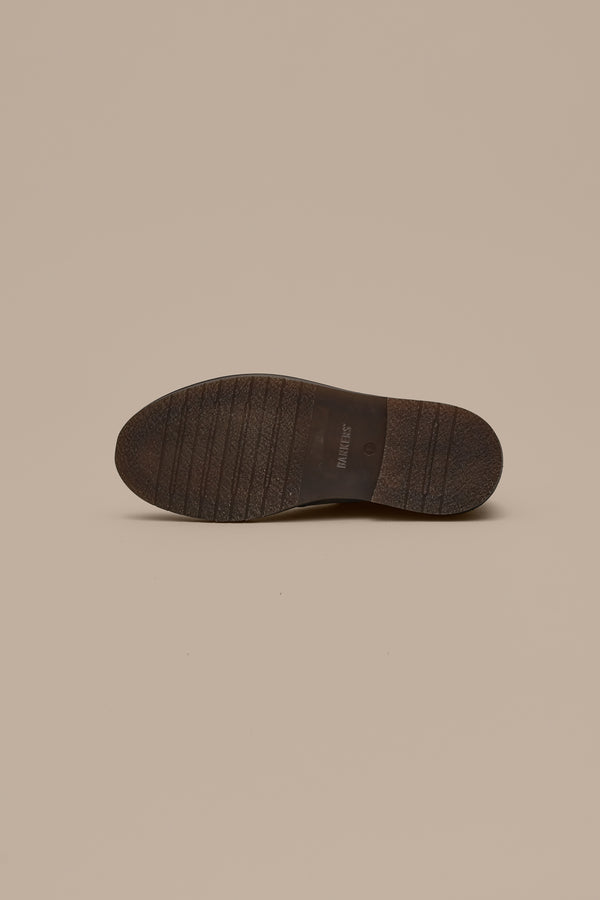 The image displays the bottom view of a Howarth Desert Boot by Barkers, featuring a dark brown sole with horizontal grooves and "Barkers" embossed in the center against a beige background—highlighting quality footwear craftsmanship.