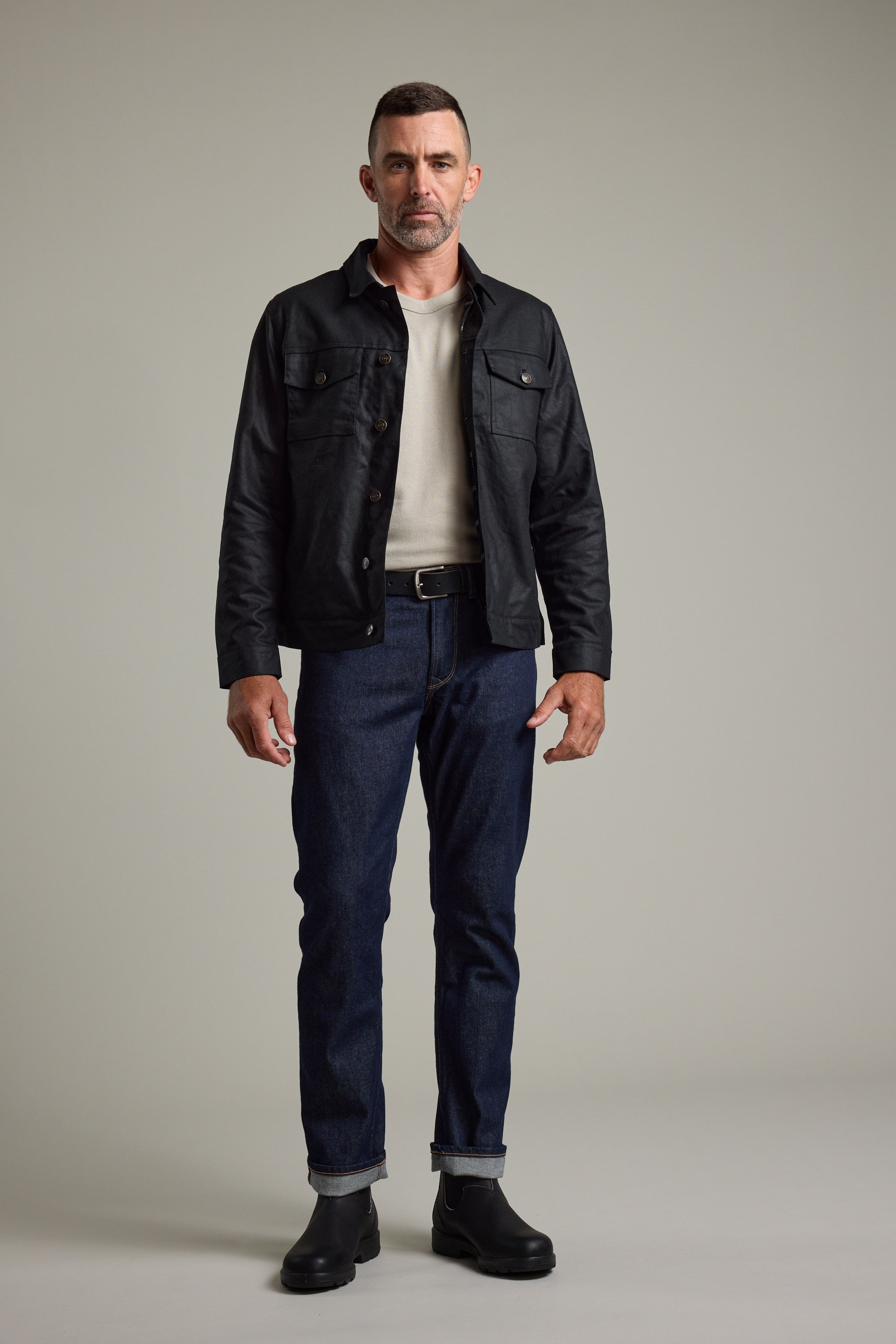 Man in Barkers Benson Waxed Cotton Jacket, white shirt, dark jeans, and black boots.