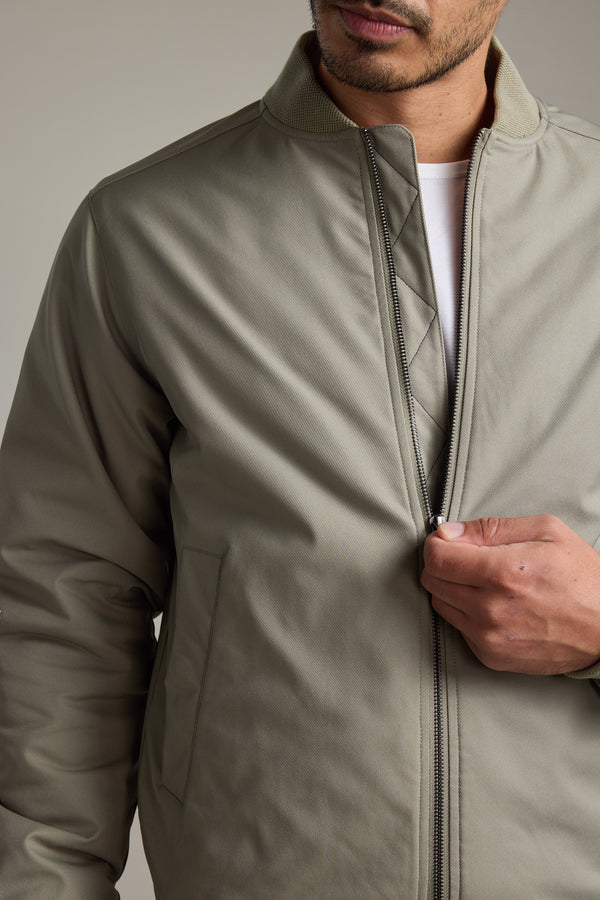 Man zipping up a Barkers Dunhill Bomber Jacket over a white shirt, shown shoulders down.