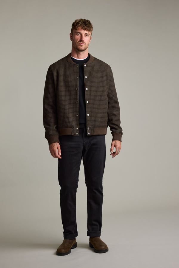 Man in Leland Wool Bomber Jacket by Barkers, black shirt, black jeans, and brown boots.