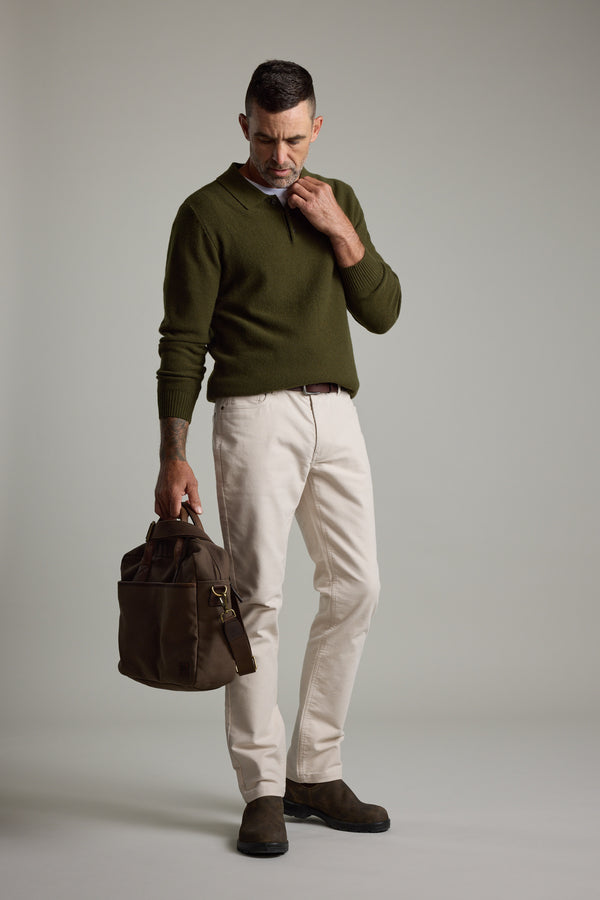 Man in Barkers Ainsley Woollen Long Sleeve Polo and light pants, holding a brown bag.