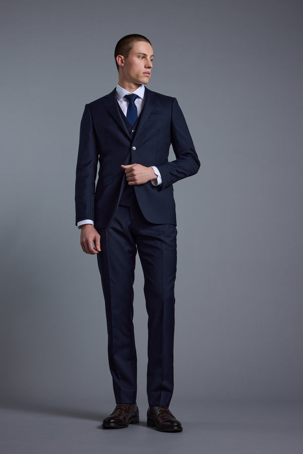 Man in Barkers Mayfair ZQrx Suit Trouser, white shirt, and tie against a gray background.