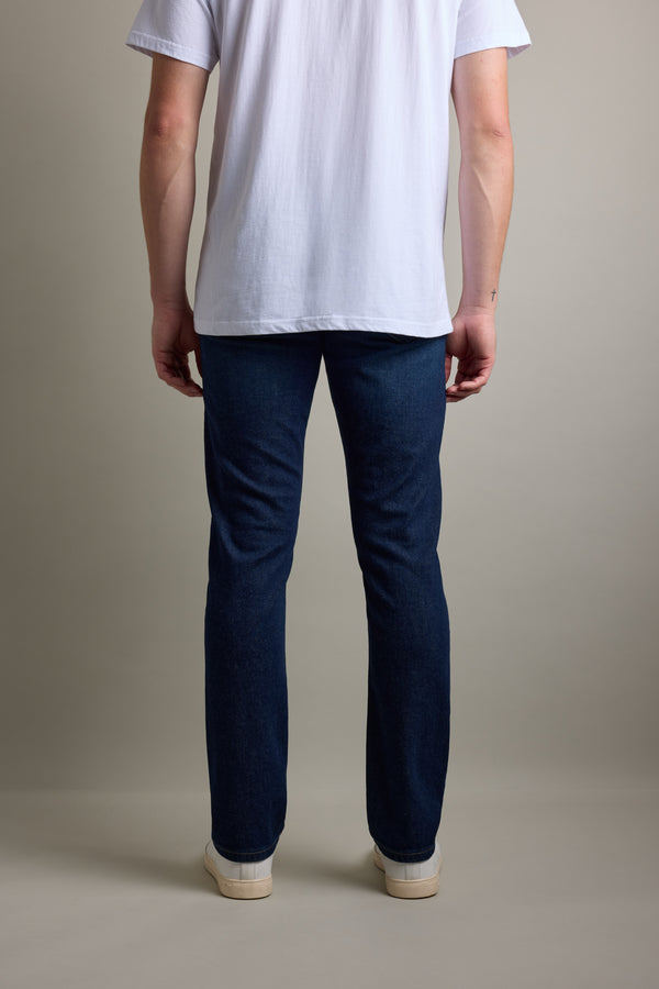 Person in Barkers Nomad Denim Taper Jeans, white tee, and white shoes, seen from the back.