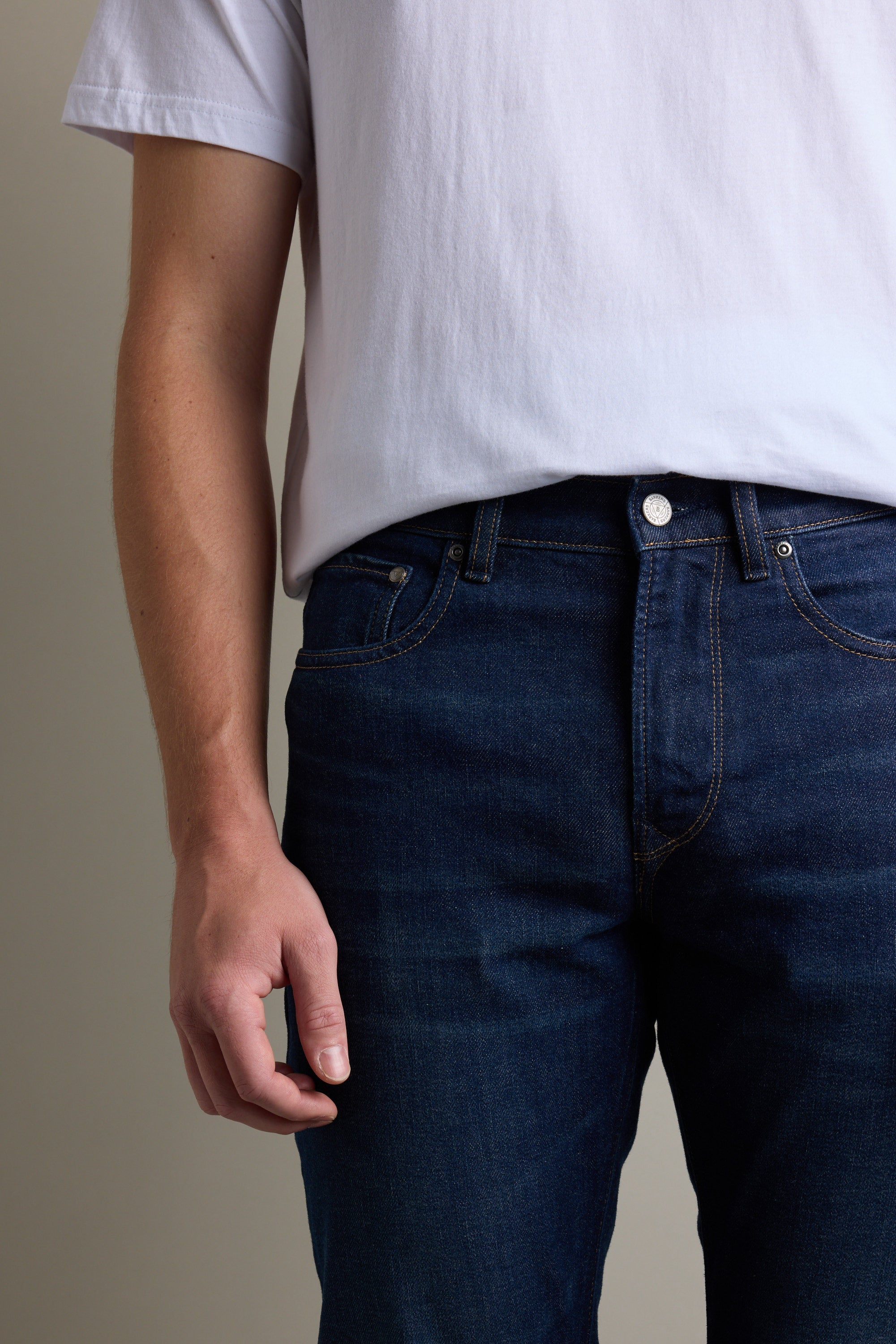 Model wears Barkers Nomad Denim Taper Jean and a white t-shirt, standing with one arm relaxed.