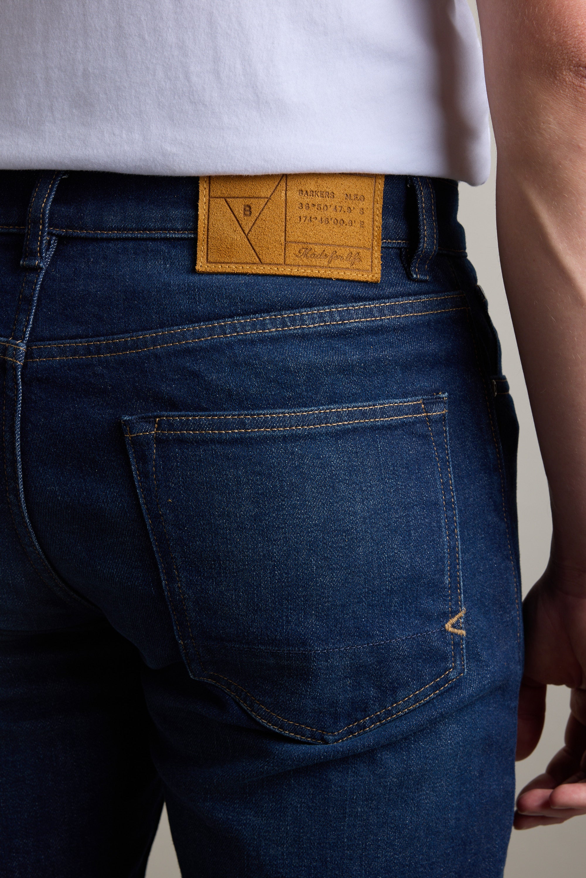 Person in Barkers Nomad Denim Taper Jean with a brown leather patch and white shirt.